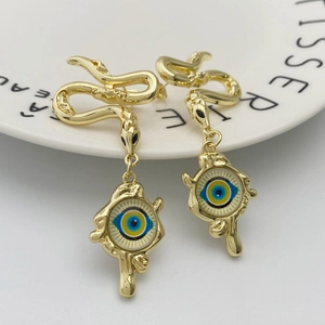 Vintage golden snake earrings featuring a blue evil eye pendant on a white background