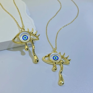Detailed macro view of vintage golden evil eye necklace with teardrop charms and blue inlay