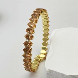 Gros plan d'un bracelet doré de luxe serti de zircons ambrés ronds en monture à griffes