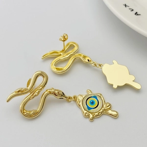 Close-up of golden snake earrings with intricate scales and blue evil eye charms