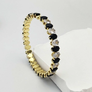 Gros plan d'un bracelet tennis réglable doré avec zircons noirs et transparents polis