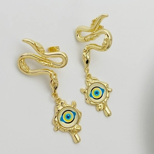 Close-up of golden snake drop earrings featuring a mystical blue evil eye pendant detail