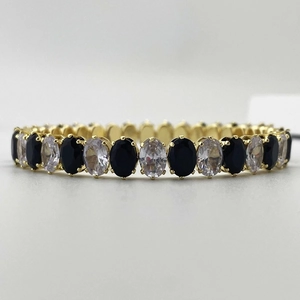 Détail macro du bracelet doré de luxe avec zircons ovales noirs et transparents