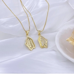 Nahaufnahme der goldenen Muschel-Anhänger mit Zirkonia-Inlays auf Seidenstoff
