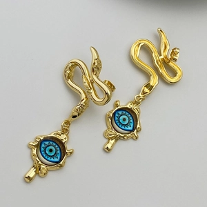 Close-up of golden snake stud earrings with blue evil eye pendant and polished finish