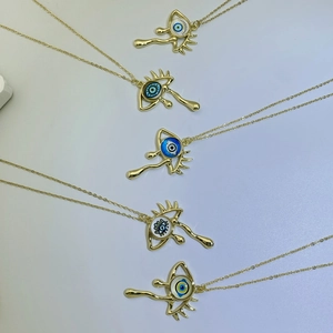 Detail of five gold evil eye pendants with colorful enamel teardrop designs on chains