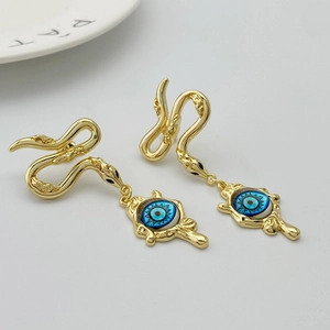 Detailed macro view of golden snake-shaped earrings with evil eye pendants for women