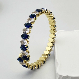 Gros plan détaillé d'un bracelet doré avec oxydes de zirconium ovales bleus et blancs