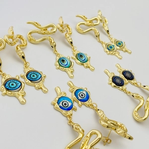 Detail of snake-shaped earrings with evil eye charms in multiple blue and green shades