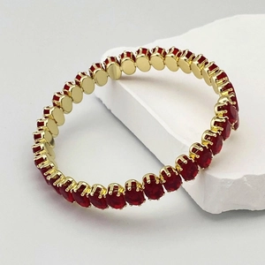 Détail d'un bracelet tennis plaqué or avec pierres ovales rouge rubis sur un support