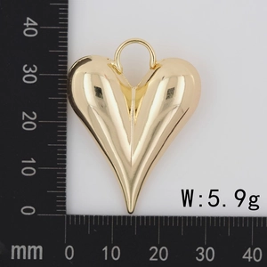 Macro detail of a 18K gold-plated heart pendant showing dimensions with a metric ruler
