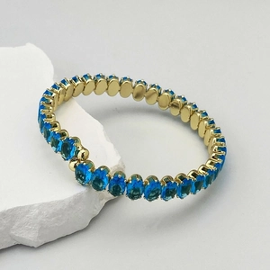 Détail d'un bracelet de tennis doré avec oxydes de zirconium bleus à coupe ovale