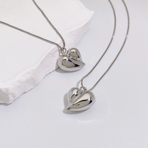 Close-up of polished silver heart pendants on delicate box chains with mineral stone
