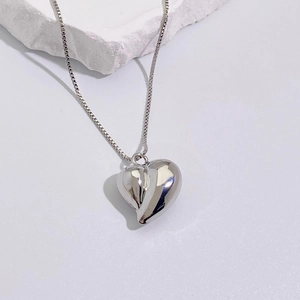 Macro detail of high-polish heart pendant and delicate silver box chain necklace