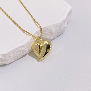 Detailed macro view of a 18K gold-plated heart pendant on a polished box chain necklace