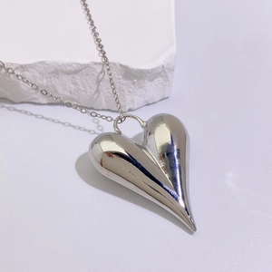 Macro shot of polished silver heart pendant necklace on a natural white stone base