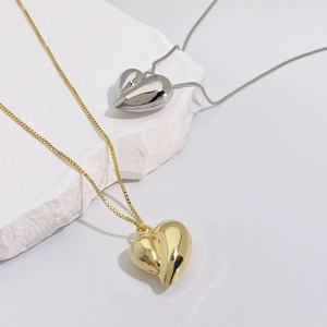 Detail of gold and silver heart pendants with mirror finish on stone platform