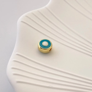 Detailaufnahme der goldenen Evil Eye Zwischenperle für DIY-Schmuck in weißer Schale