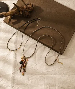 Dettaglio della collana vintage tessuta a mano con pietre colorate, fiori e nappe in metallo