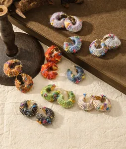 Detailed view of colorful knitted wool hoop earrings with gold metal clasps in warm tones