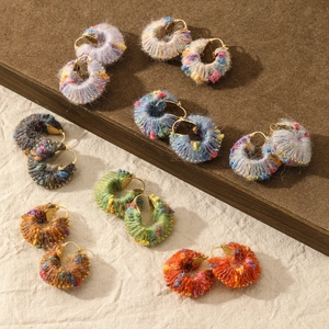 Detail of colorful handcrafted wool yarn wrapped gold hoops in various mixed color patterns