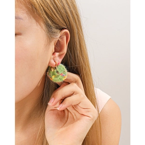 Close-up of grass green hand-knitted woolen hoop earrings with colorful fiber details