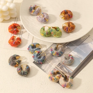 Detailed close-up of mixed colorful wool yarn knitted hoop earrings on decorative tray