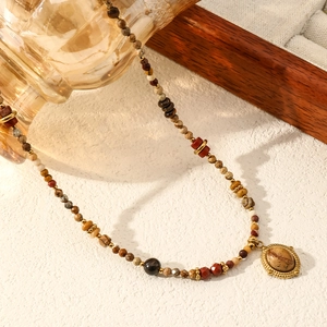Detailed macro of bohemian stone beaded necklace with vintage golden oval pendant