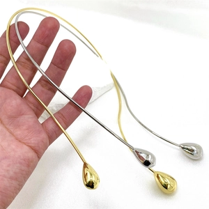 Detail showing minimalist gold and silver teardrop pendant collars held in hand