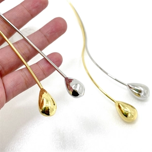 Close-up of golden and silver water drop shape long metal hairpins on fabric