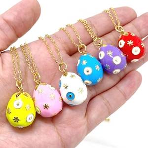 Detailed view of six colorful enamel Easter egg pendants held in hand with gold chain