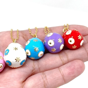Macro shot of colorful 14K gold plated Easter egg pendants with enamel evil eye patterns