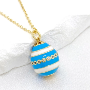 Detail of 14K gold Easter egg pendant with blue enamel stripes and zircon accents
