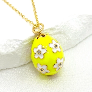 Macro detail of 14K gold Easter egg pendant with yellow enamel and white floral pattern