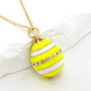 Macro shot of yellow and white striped Easter egg pendant with sparkling zircons