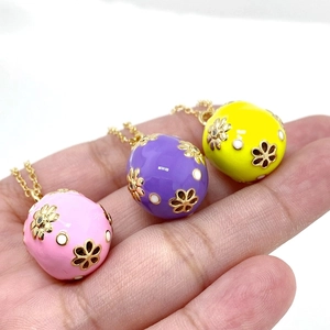 Detailed macro view of 14K gold enamel Easter egg pendants with floral relief motifs