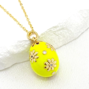Macro shot of 14K gold plated yellow enamel Easter egg pendant with floral crystal inlay