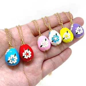 Detail of six colorful enamel Easter egg pendants with white floral patterns on gold chains