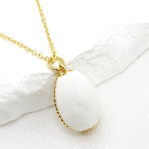 Detailed close-up of 14K gold-plated oval white pendant with elegant wavy metal edge