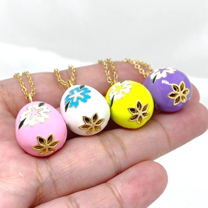 Macro view of four colorful 14K gold-plated Easter egg pendants with enamel floral patterns
