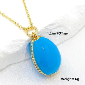 Detail view of 14K gold enamel egg pendant with blue stone measuring 14mm by 22mm