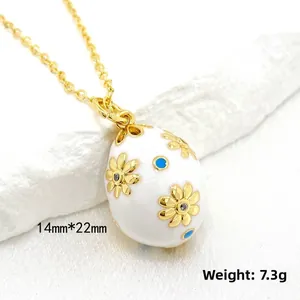 Detailed close-up of 14K gold-plated white enamel Easter egg pendant with floral patterns