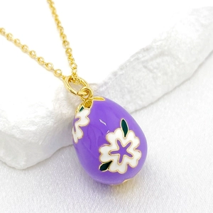 Detailed close-up of 14K gold-plated Easter egg pendant with purple enamel and white flowers