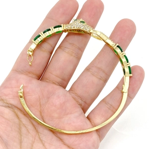 Detalle del brazalete de serpiente dorado con pavé de circonitas y gemas verdes