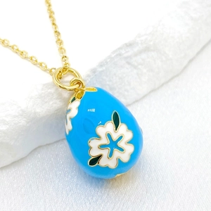 Blue enamel Easter egg pendant necklace with gold floral details on white rock