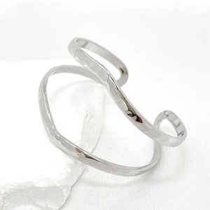 Minimalist silver wavy open bangle with hammered texture on white stone base