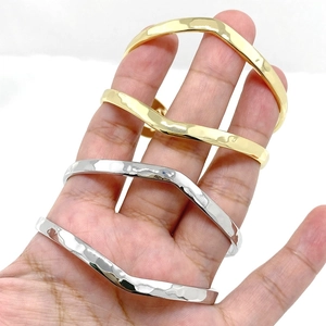 Detail of wavy hammered texture on silver and gold cuff bangles held in hand