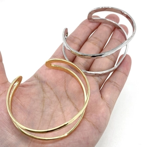 Detail of open cuff bracelets showing gold smooth finish and silver hammered texture metal