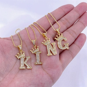 Détail de pendentifs couronne dorés K, I, N, G avec cristaux de zircone micro-pavés