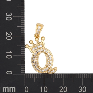 Détail macro du pendentif lettre Q couronne dorée serti de zircons avec une règle